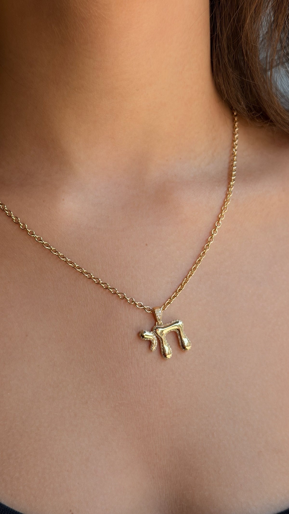 aclose up look of a buuble chai diamond and gold pendant in yellow gold , lifestyle