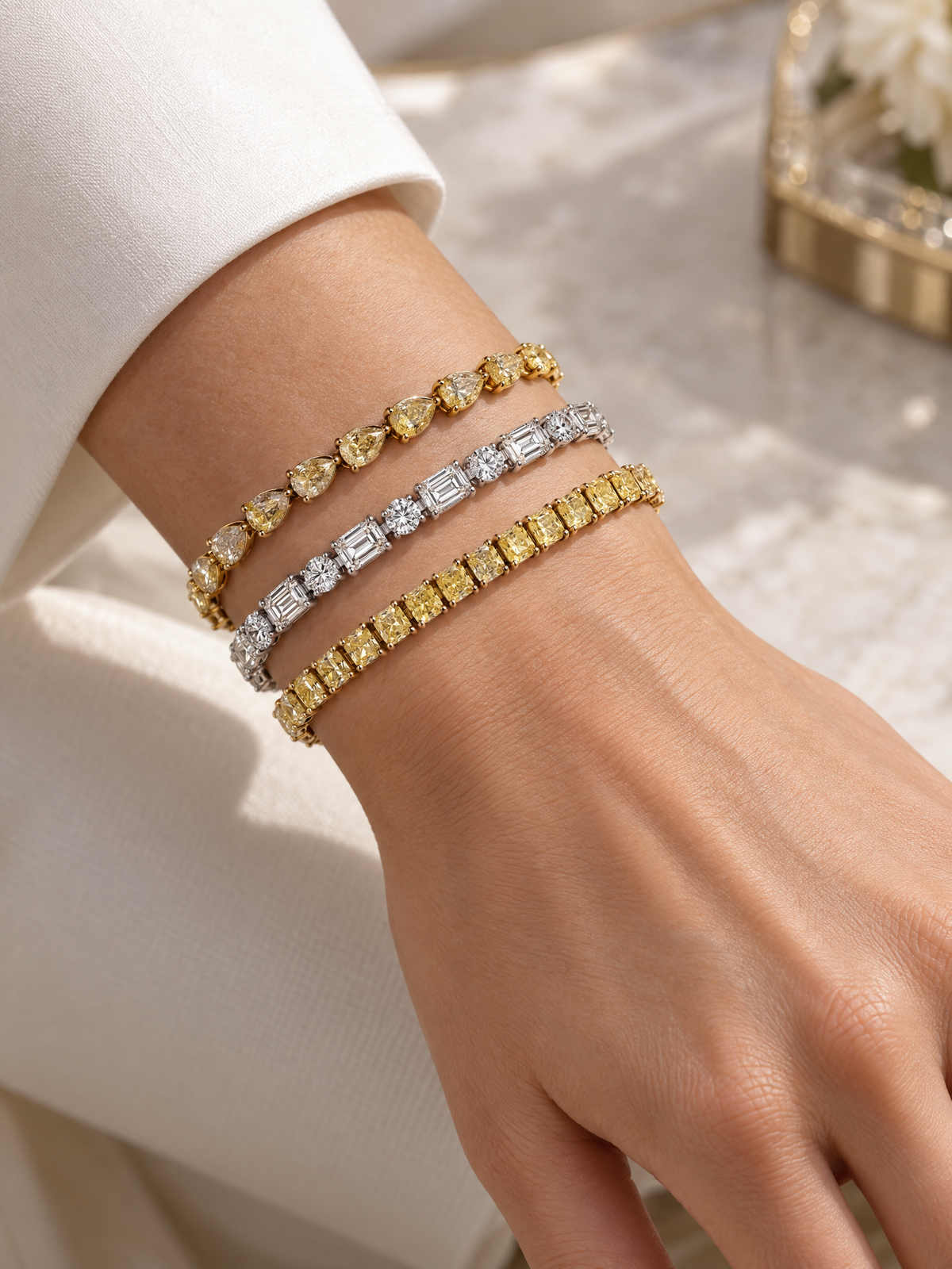 Three fine jewelry tennis bracelets with yellow, white, and yellow 18K Gold diamonds on a model's wrist from The Private Room Fine Jewelry