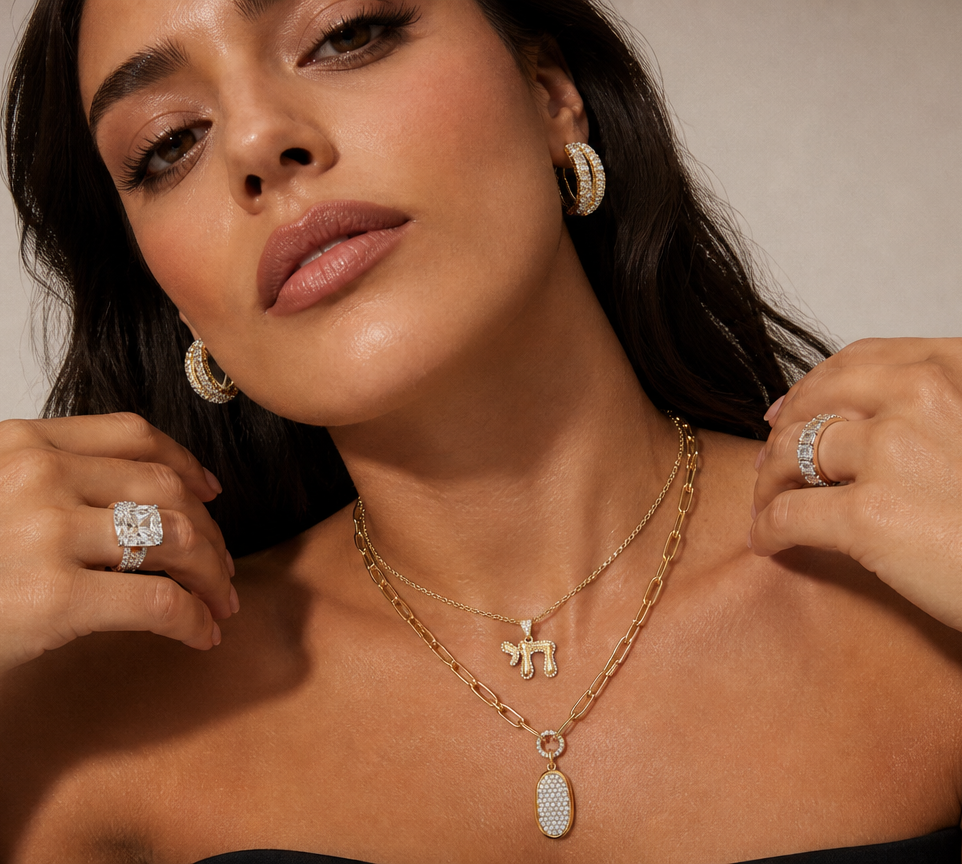 A close-up lifestyle shot of a woman wearing 18K gold fine jewelry, featuring a gold diamond pendant paperclip oval chain necklace and bubble chai pendant with gold chain from The Private Room Fine Jewelry