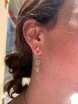 Lifestyle - Love letter falling earrings on ear in 18k rose gold