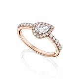 A rose gold halo ring featuring a pear-cut center stone surrounded by small round stones, with additional stones along the split band, shown on a clean white background with a soft reflection.